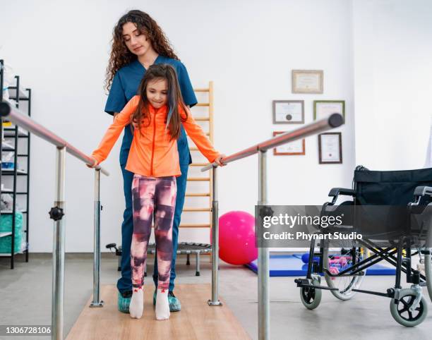 jonge patiënt die fysiotherapie bij een kliniek met hulp van een therapeut doet - rehabilitation stockfoto's en -beelden