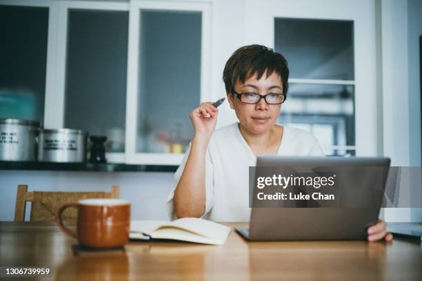 asian senior woman working on her home finance with laptop at home - investing for retirement imagens e fotografias de stock