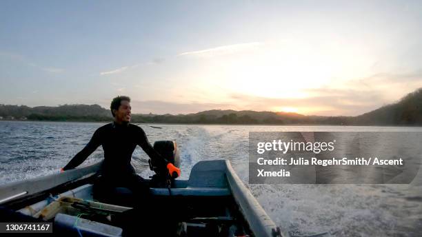 man drives motorboat out to sea in early morning - los santos inocentes fotografías e imágenes de stock