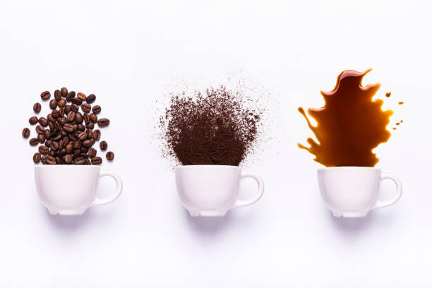 three white cups with coffee beans, ground coffee, and brewed coffee knocked off from each cup
