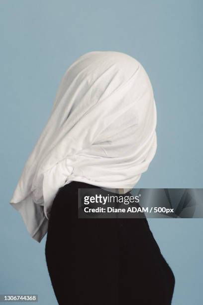 side view of woman wearing hijab while standing against white background - velo foto e immagini stock