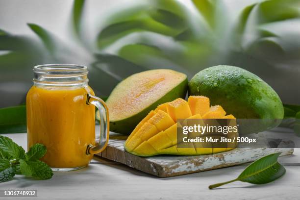 close-up of mango and juice on table - マンゴー ストックフォトと画像