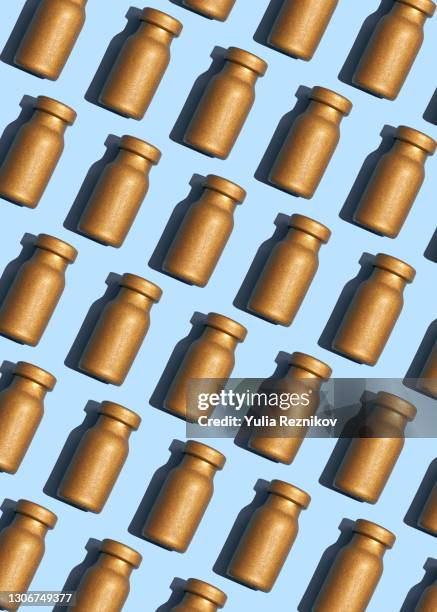 gold colored vaccine vials on the blue background - cologne bottle stock pictures, royalty-free photos & images