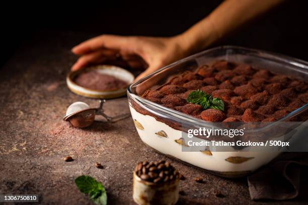 cropped hand holding dessert in bowl on table - tiramisu stock pictures, royalty-free photos & images