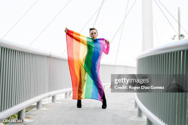 bisexual man with rainbow flag standing on street - men doing quirky things stock-fotos und bilder