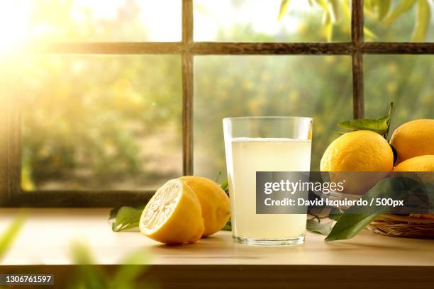 close-up of orange juice with lemon and lemon on table - lemon juice stock pictures, royalty-free photos & images