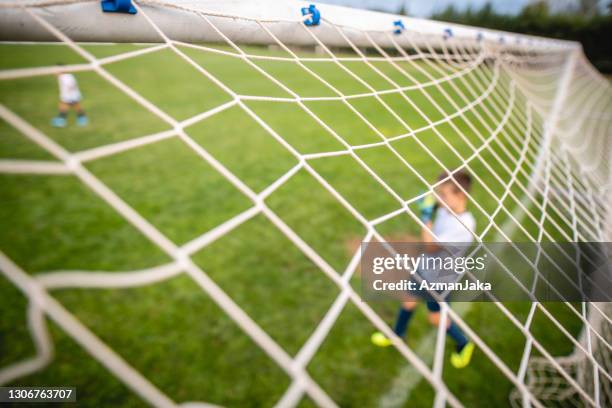 pre-adolescent boy footballer guarding goal - boy goalie standing in front of goal net stock pictures, royalty-free photos & images