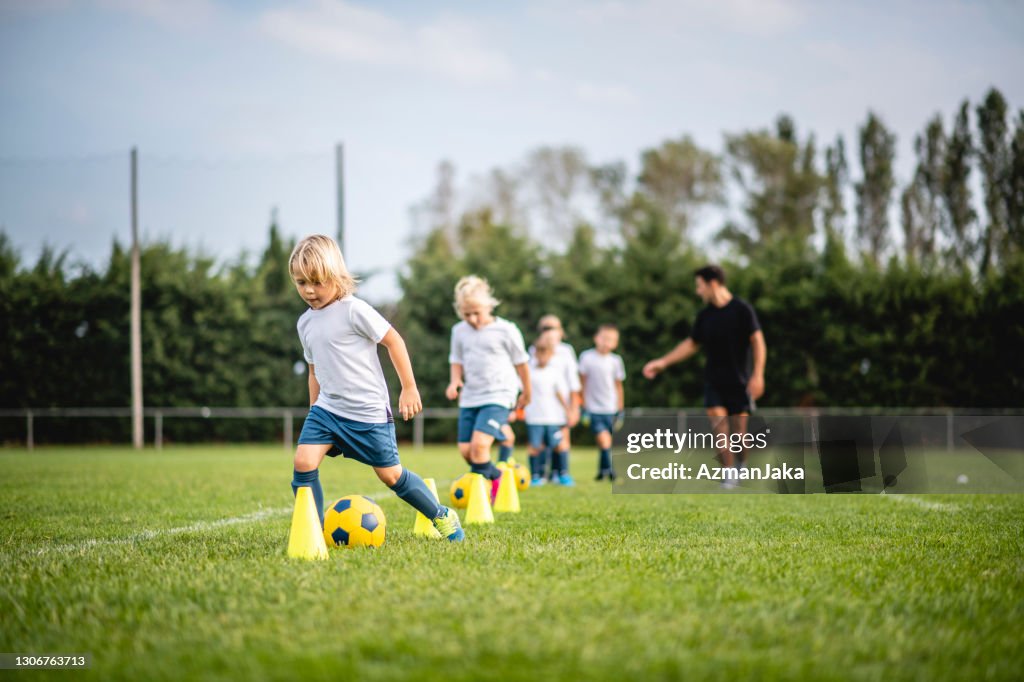 Pre-adolescente voetballers dribbelen rond pylonen