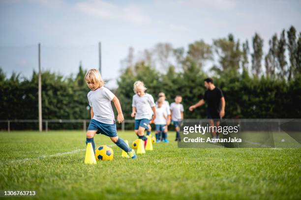 pre-adolescent footballers dribbling around pylons - talent team coaching imagens e fotografias de stock
