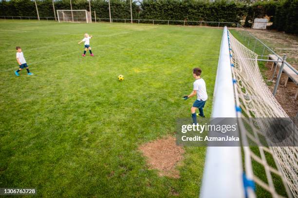 young boy footballer standing guard at goal - boy goalie standing in front of goal net stock pictures, royalty-free photos & images