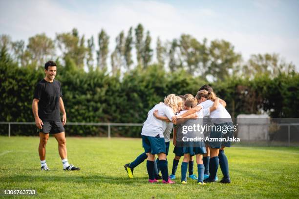 young boy and girl footballers huddling during practice - huddle sport girls stock pictures, royalty-free photos & images