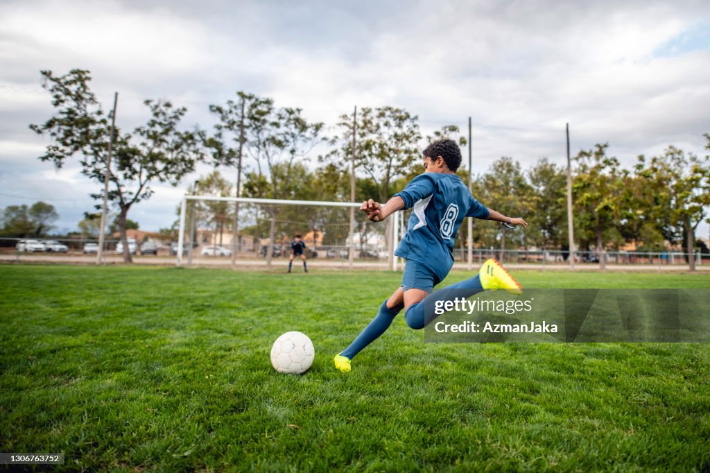 Athletic Mixed Race Boy Footballer Approaching Ball for Kick