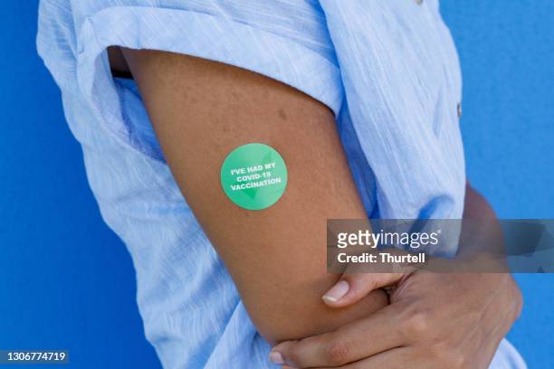 close up of arm of african woman with covid-19 vaccine sticker - covid 19 vaccine stock pictures, royalty-free photos & images