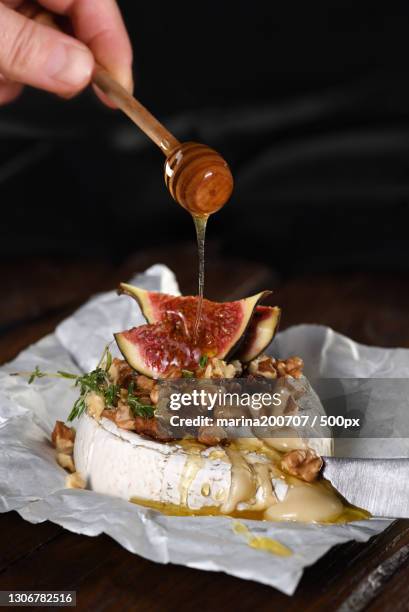 cropped hand pouring honey on table - baked brie stock pictures, royalty-free photos & images