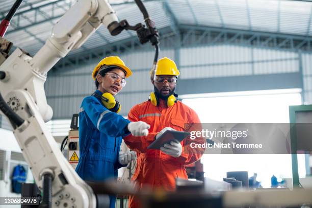 female quality engineer and male production engineer talking at welding robot in a factory. cost reduction in manufacturing process concepts. - skill development foto e immagini stock