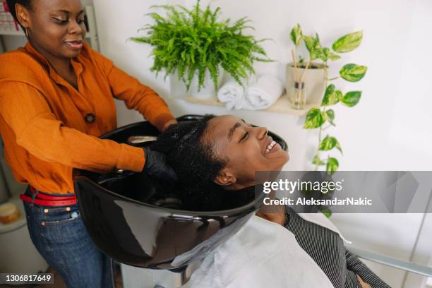 het wassen van haar in een kapsalon - hairdressers black woman stockfoto's en -beelden