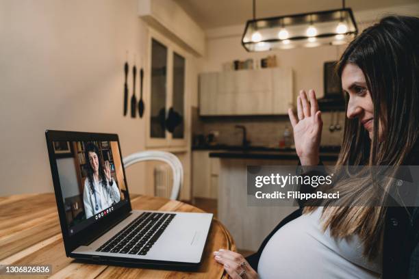 de jonge zwangere vrouw heeft een videogesprek met haar arts - pregnant women greeting stockfoto's en -beelden