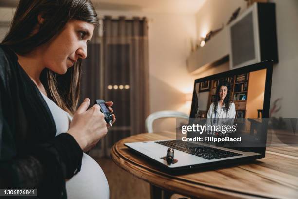 de jonge zwangere vrouw heeft een videogesprek met haar vrouwelijke arts terwijl zij haar bloedsuikercurve test - pregnancy class stockfoto's en -beelden