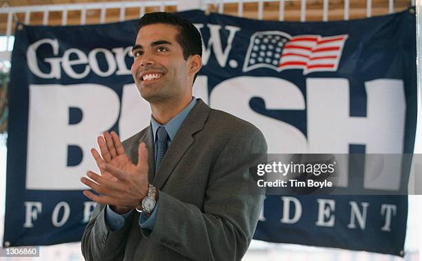 George P. Bush applauds as he stands in front of a "George W. Bush For President" poster during a campaign stop July 26, 2000 in Aurora, Illinois....