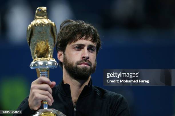 Nikoloz Basilashvili of Georgia poses with the trophy following victory in The Qatar ExxonMobil final between Roberto Bautista Agut and Nikoloz...