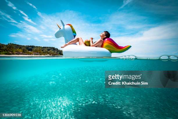 girl lying on a floating unicorn with fish swimming underwater - relax vacation fotografías e imágenes de stock