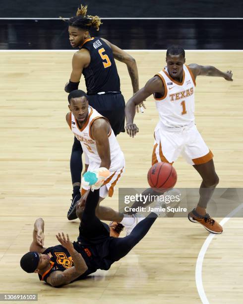 Avery Anderson III of the Oklahoma State Cowboys falls to the ground over a loose ball as Matt Coleman III and Andrew Jones of the Texas Longhorns...