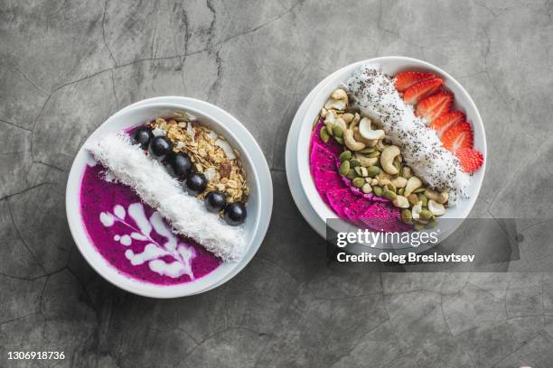 top view of two healthy vegan smoothie bowls on gray concrete background - acai berries stockfoto's en -beelden