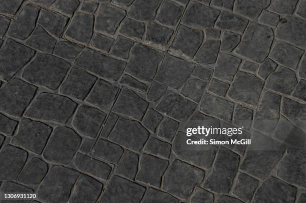 stencilled dark grey concrete patio in a rock flagstone pattern - adoquinado fotografías e imágenes de stock