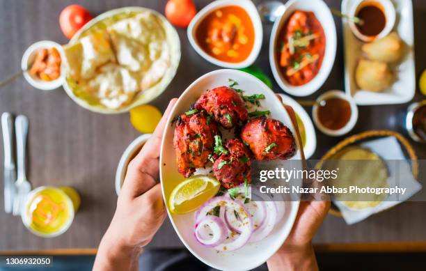 holding chicken tikka dish in hand. - indiase gerechten stockfoto's en -beelden