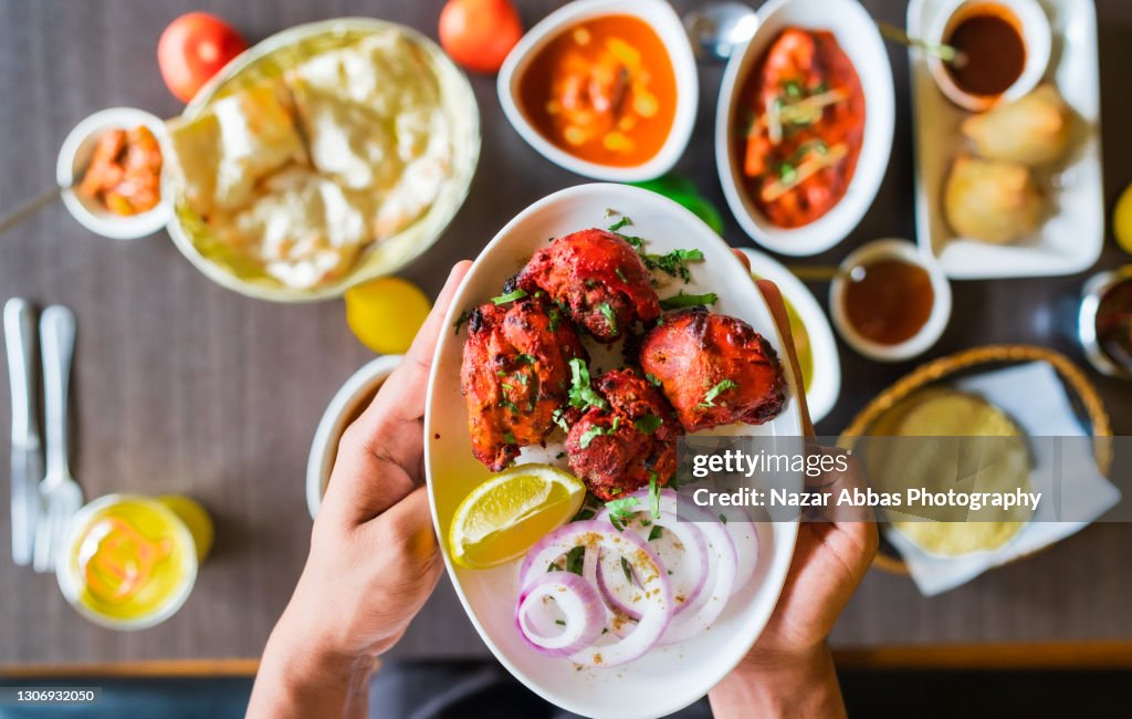 Holding chicken tikka dish in hand.