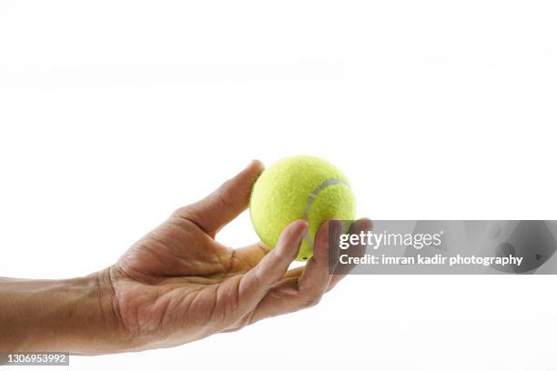 left hand holding tennis ball in isolated white background - tennisball stock-fotos und bilder
