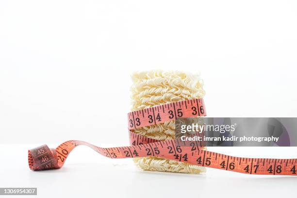 measuring tape on maggi food. conceptual image for diet food. - maggi noodles stock pictures, royalty-free photos & images