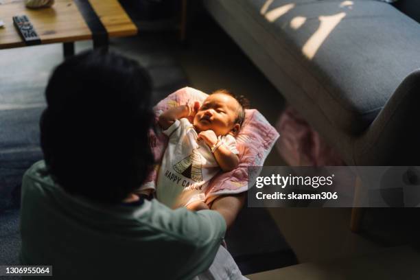 asian grandmother be loving and holding asian baby with contrast lighting at home - glamourous granny stockfoto's en -beelden