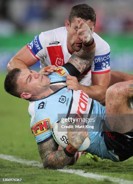 Josh Dugan of the Sharks is tackled by Andrew McCullough of the Dragons during the round one NRL match between the St George Illawarra Dragons and...