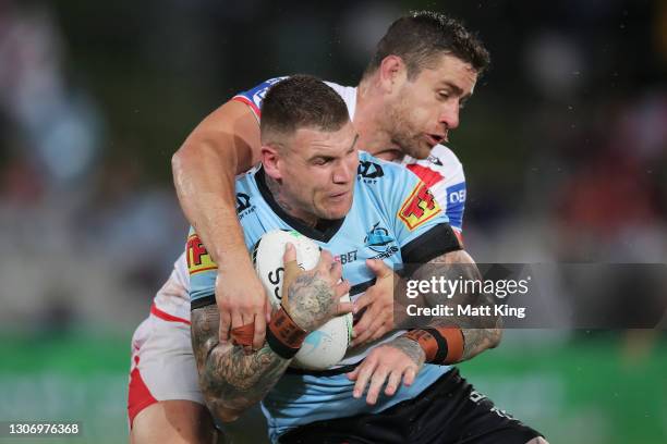 Josh Dugan of the Sharks is tackled by Andrew McCullough of the Dragons during the round one NRL match between the St George Illawarra Dragons and...