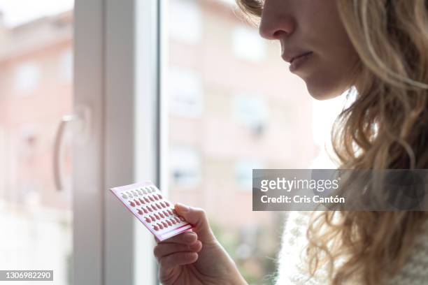 young woman holding contraceptive pills - anticonceptivo fotografías e imágenes de stock