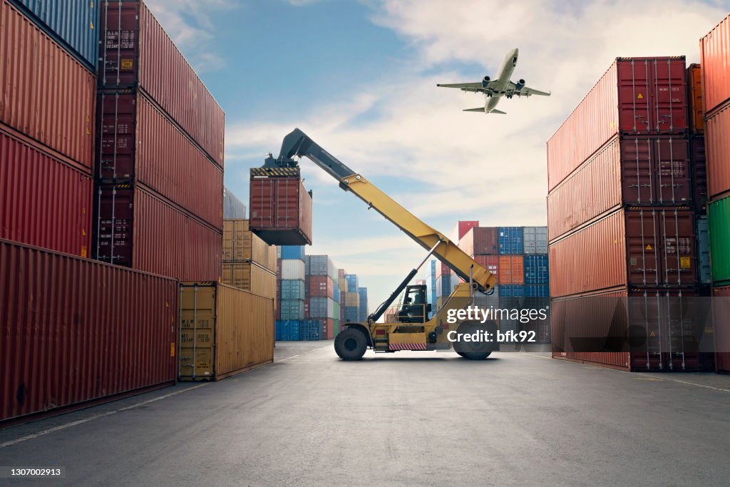 Flugzeug fliegt über Containerhafen.