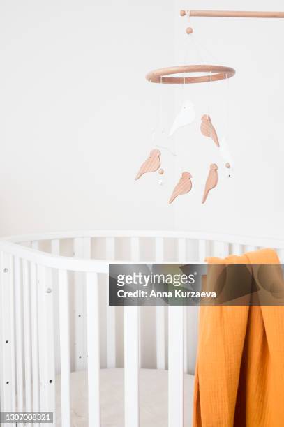 close up view of baby room with a white baby bed and a baby mobile hanging over the bed, selective focus. nursery interior. - modern baby nursery stock-fotos und bilder