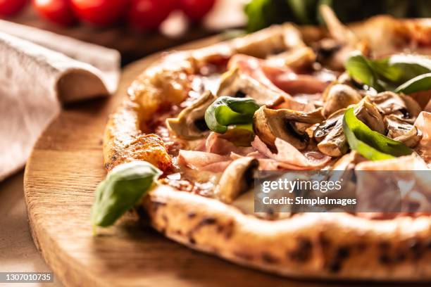 pizza baked with mushrooms and ham with fresh basil on top. - prosciutto pizza foto e immagini stock