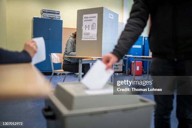 Member o the public casts their ballot in the state elections in Rhineland-Palatinate during the coronavirus pandemic on March 14, 2021 in Mainz,...