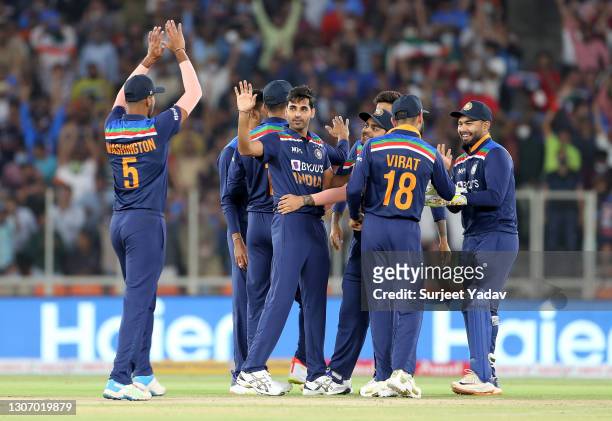 Bhuvneshwar Kumar of India celebrates after taking the wicket of Jos Buttler of England with team mate Washington Sundar during the 2nd T20...
