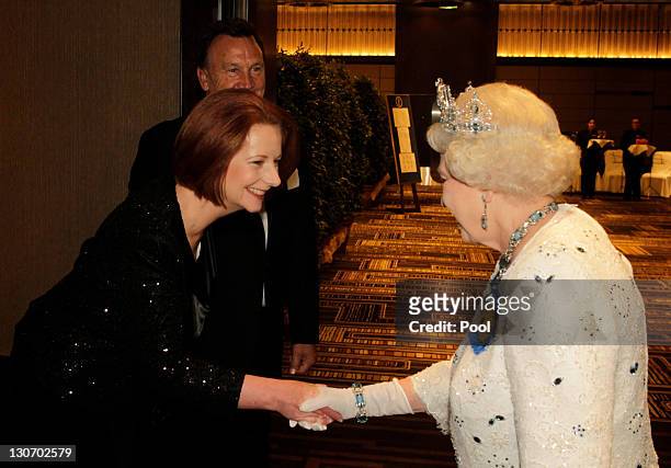 Queen Elizabeth II shakes hands with Australia's Prime Minister Julia Gillard, beside Ms Gillard's partner Tim Mathieson, on arriving at a banquet as...