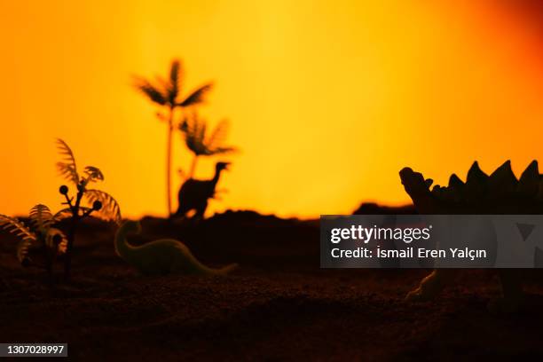 dinosaurs walking in the desert at sunset - extinct stock pictures, royalty-free photos & images