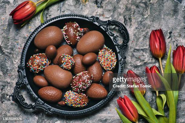 schokolade ostereier und rote tulpen auf einem tisch ansicht - chocolate top view stock-fotos und bilder