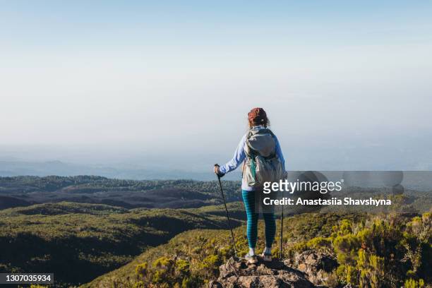 young woman hiker reaching the top enjoying the scenic mountain view in kilimanjaro national park - mt kilimanjaro stock pictures, royalty-free photos & images