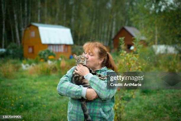 vrouw die haar kat in openlucht kust - cat cuddle stockfoto's en -beelden