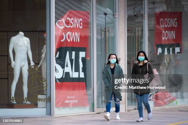 Two women wearing face masks walk past a store with a closing down sign in Cardiff city centre on March 13, 2021 in Cardiff, Wales. Wales First...