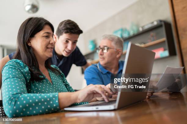 parents doing home finances and talking to teenager son - mature woman and son imagens e fotografias de stock