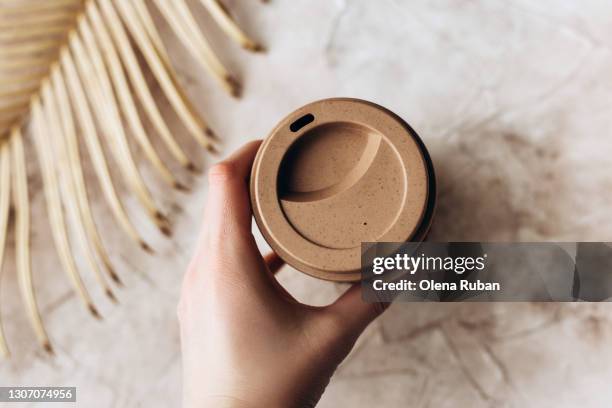 female hand holding an eco glass next to a dried leaf - coffee cup takeaway stock-fotos und bilder