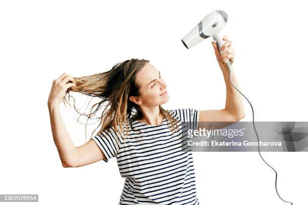 young woman with wet hair blow-drying her hair on a white isolated background. - cheveux secs photos et images de collection